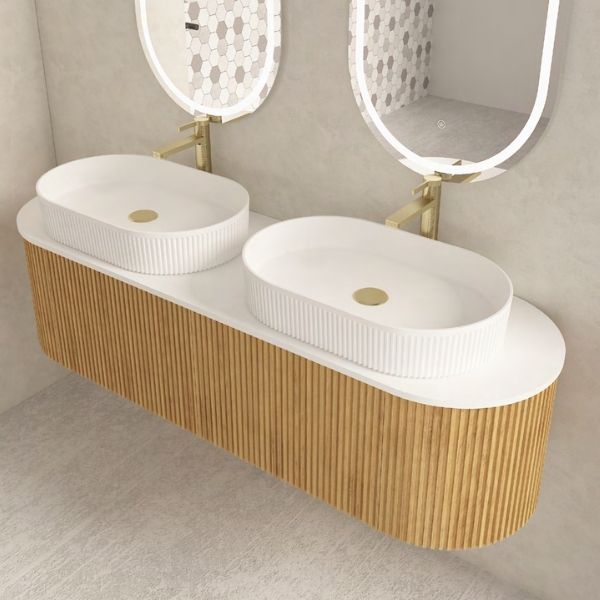 Elegant double vanity with a ribbed walnut wood finish and two oval above-counter ceramic basins, paired with dual oval LED mirrors. Set against a neutral wall with natural light and indoor plants for a refreshing and modern aesthetic.