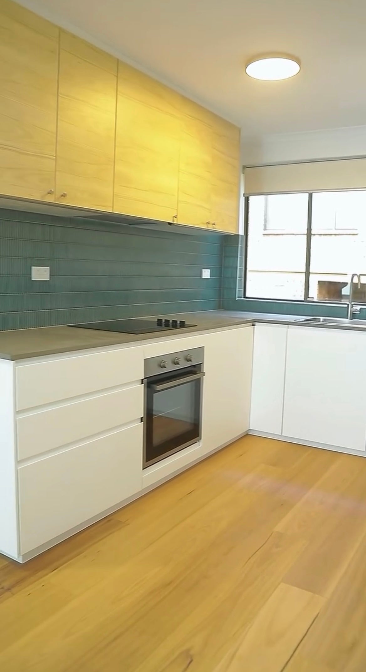 Completed kitchen renovation with timber cabinetry and teal splashback — Renova Build Sydney project