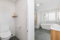 Separate toilet compartment with a smart bidet toilet and timber corner shelf, opening onto the main bathroom