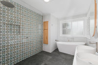 Renovated bathroom in West Pennant Hills with a floor-to-ceiling patterned feature wall, freestanding bath, twin basins and charcoal stone-look floor tiles