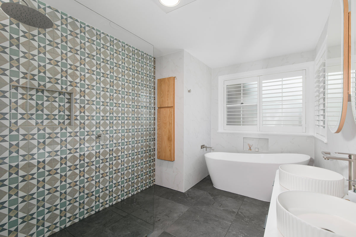 Renovated bathroom in West Pennant Hills with a floor-to-ceiling patterned feature wall, freestanding bath, twin basins and charcoal stone-look floor tiles